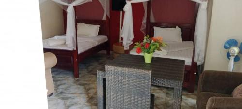 a room with two beds and a table with flowers on it at Gorilla African Guest House in Entebbe