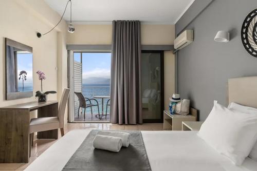a bedroom with a bed and a desk with a view of the ocean at Calamos Beach Family Club in Kalamos