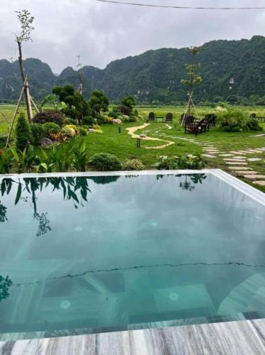 an empty swimming pool with a view of a field and mountains at Tam Coc Horizon Retreat in Vũ Lâm