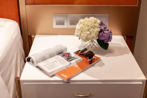 a table with a vase of flowers and a book at La Seine Hotel in Vientiane