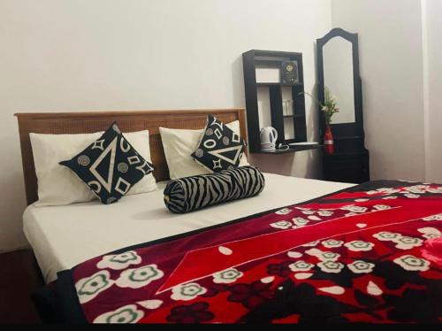 a bedroom with a bed with a red blanket and pillows at King's Lodge in Nuwara Eliya