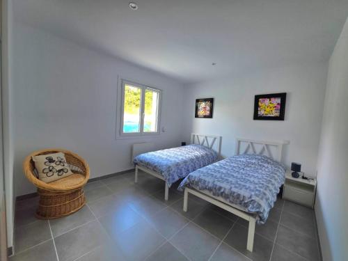 a bedroom with two beds and a chair at Gîte le Brahmã in Châteauneuf-sur-Isère