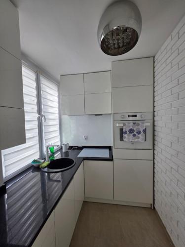 a kitchen with white cabinets and a black counter top at Apartament Klonowa in Kraśnik
