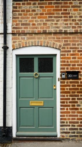 a green door in a brick building with a brick wall at Hazelbury Cottage in Wilton