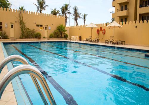 a swimming pool at a resort with chairs and umbrellas at Golfside Serenity - Stylish 1 BHK by FREE Holiday Homes in Ras al Khaimah