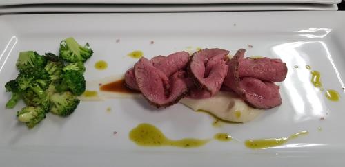 a white plate with some meat and broccoli on it at Hotel Bergblick in Racines