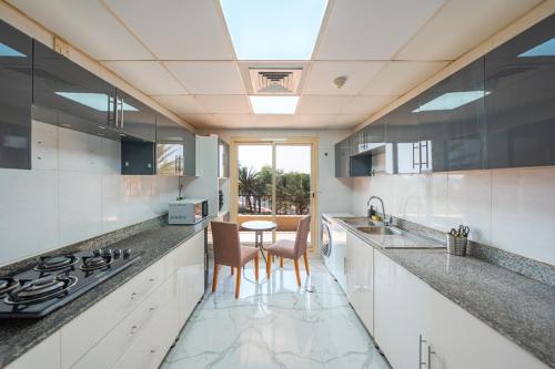 a kitchen with white cabinets and a table with chairs at Golfside Serenity - Stylish 1 BHK by FREE Holiday Homes in Ras al Khaimah
