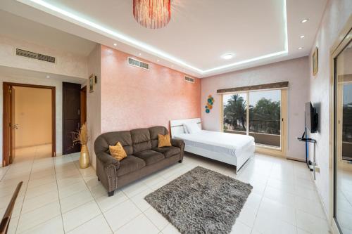 a living room with a couch and a tv in it at Golfside Serenity - Stylish 1 BHK by FREE Holiday Homes in Ras al Khaimah