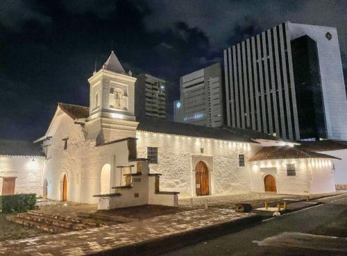 a white church with a clock tower at night at Bau 420 HOSTAL in Cali