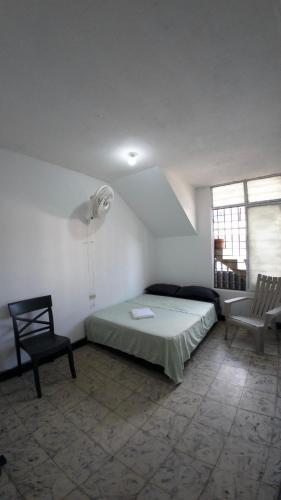 a bedroom with a bed and a chair in a room at Bau420! Backpackers HOSTAL in Cali