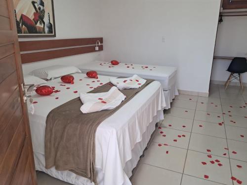 two beds in a room with red roses on the floor at Suítes Flecheiras in Flecheiras