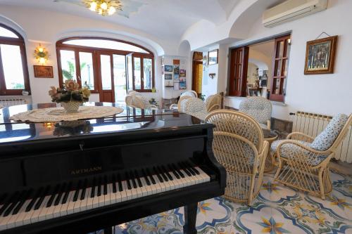 a piano in a room with chairs and a table at Hotel Residence - Parco Mare Monte in Ischia
