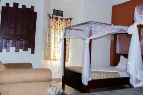 a bedroom with a canopy bed and a couch at Gorilla African Guest House in Entebbe