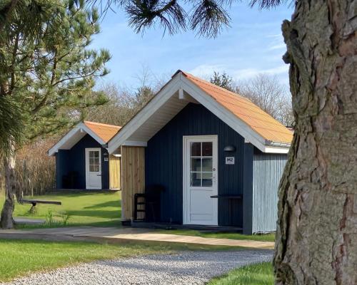 a blue shed with a white door and a tree at Ribe Camping in Ribe