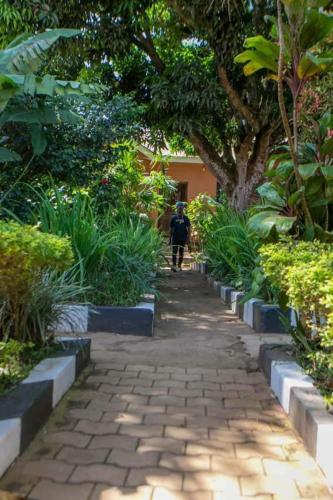 a person walking down a path in a garden at Gorilla African Guest House in Entebbe
