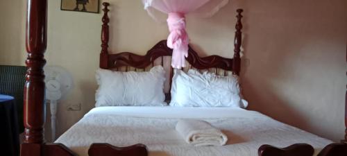 a bed with a wooden headboard with a pink ribbon at Gorilla African Guest House in Entebbe