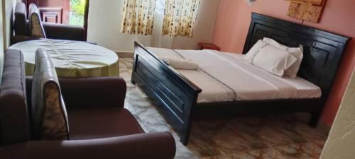 a bedroom with a bed and a chair and a table at Gorilla African Guest House in Entebbe