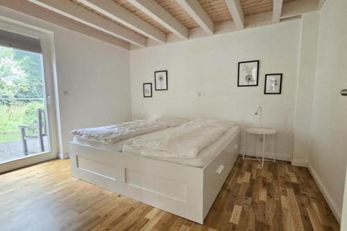 a white bedroom with a bed and a window at Dock 2 - tolles Ferienhaus für bis zu 6 Personen mit Kaminofen und Sauna - Haustiere herzlich willkommen in Nordhorn