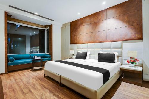 une chambre avec un grand lit et un canapé bleu dans l'établissement Super Townhouse Chhatarpur Near Metro Park, à Jāmb