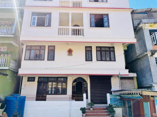 Casa blanca con puertas y ventanas negras en Hotel Tashiling Stay, en Pelling
