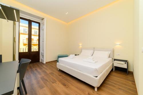 a white bedroom with a white bed and a table at Fiorentino Luxury Home Sorrento Center in Sorrento