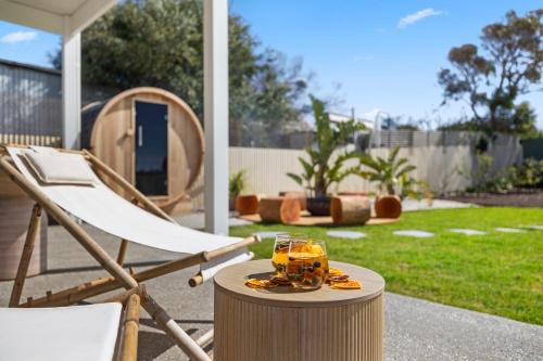 a chair and a drink on a table in a yard at YARLU by Silver Sands in Aldinga Beach
