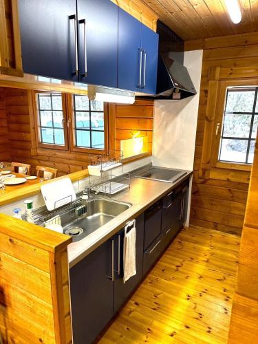 a kitchen with a sink and blue cabinets and wood floors at Furano Private Villa Runway 15 in Wada