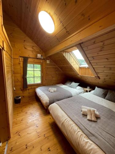 a bedroom with two beds in a log cabin at Furano Private Villa Runway 15 in Wada
