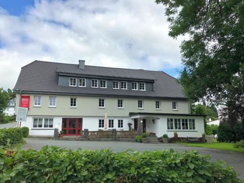 a white house with a red door at Winterberg Gruppenhaus mit Sauna ideal für Familien & Freunde in Winterberg