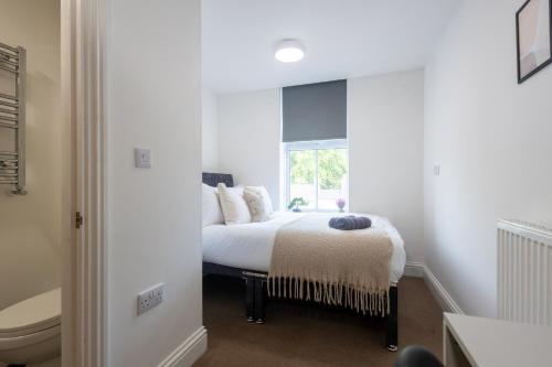 a white bedroom with a bed and a window at St James Court Aparthotel in Derby