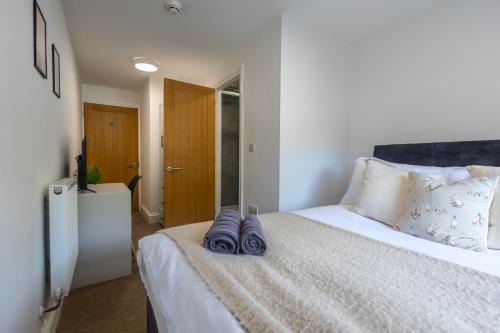a bedroom with a bed with two pairs of slippers on it at St James Court Aparthotel in Derby