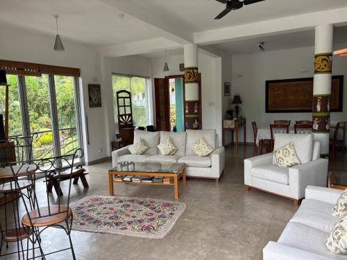 a living room with white couches and a table at Riverside Suites in Kandy