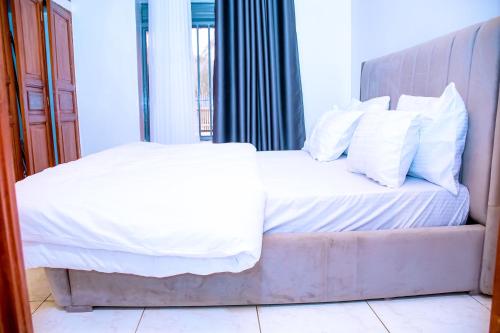 a bedroom with a bed with white sheets and pillows at BINKS appartement in Kigali