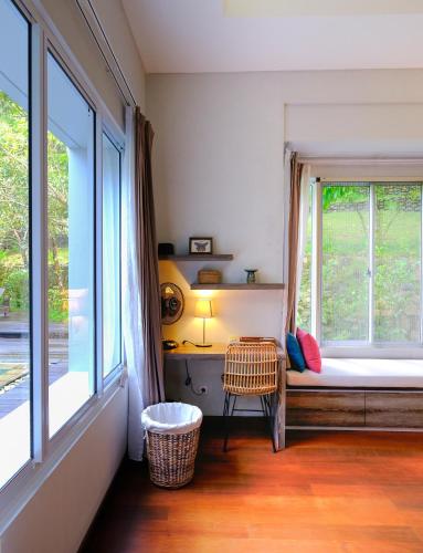 a bedroom with a window with a bed and a chair at La Quoriena Botanical Villa & Cafe' in Labuan Bajo