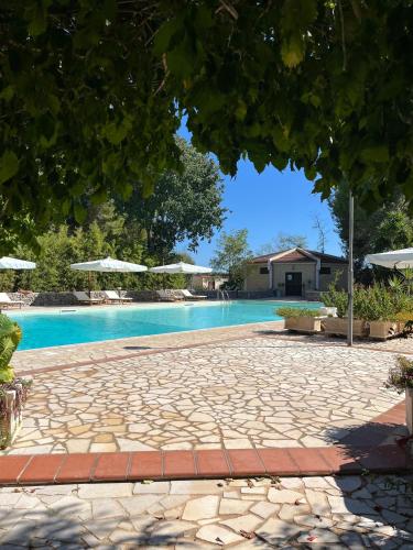 a swimming pool with a stone walkway next to a house at Casette Masseria La Camardia in Sava