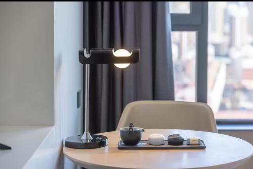 a table with a lamp and a chair in a room at Jinyi Hotel Hohhot Zhaojun Road South Second Ring Road Branch in Hohhot