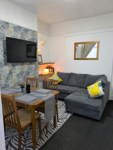 a living room with a couch and a table at Kettering 4 night min stay with Shared Bathroom, lounge TV & kitchen free WIFI Genius on longer regular stays Professional workers Rooms in Kettering