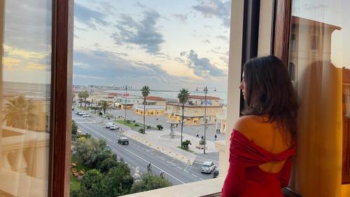 a woman looking out a window at a city street at Villa Tina Hotel in Viareggio