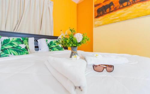 a bed with a vase of flowers and glasses on it at MANDARIN LODGE by victor in Hua Hin
