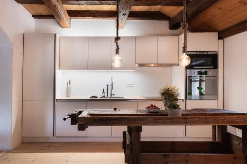 a kitchen with white cabinets and a wooden table at HØV - Boutique-Apartments im Allgäu - Rückzug & Design in Altusried