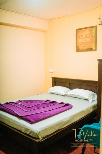 a bed in a room with a purple blanket on it at Shenga Palace by truvalue hospitality in Jāmb