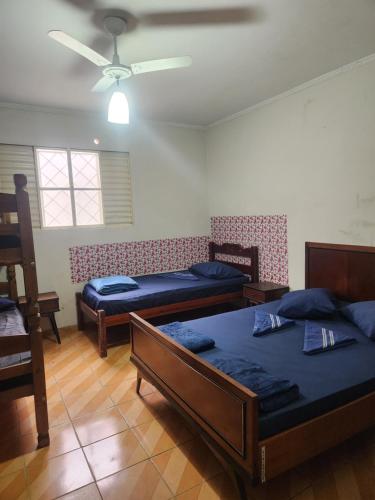 a room with three beds and a ceiling fan at Casa tamanho Família Aconchegante in Bauru