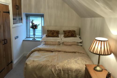 a bedroom with a bed with a lamp and a window at Chic 2 Bed Peak District Cottage Barn Alton Towers in Waterfall