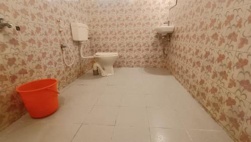 a bathroom with a toilet and a trash can at Happy Land in Varkala