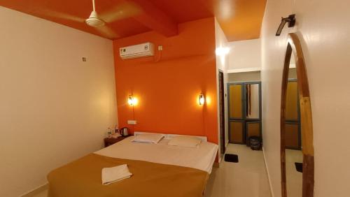 a small room with a bed with an orange wall at Happy Land in Varkala