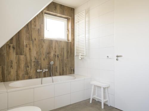 a white bathroom with a tub and a stool at Lush Villa in De Cocksdorp Texel with Steambath in De Cocksdorp
