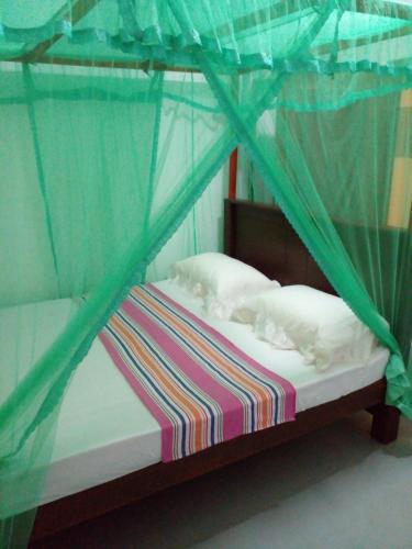 een klein bed met een hemelbed en witte lakens bij Gem Villa in Weligama