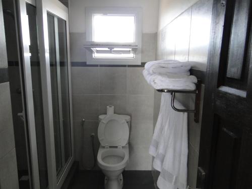 a bathroom with a toilet and a window and towels at HOTEL H1 ISALO in Ranohira