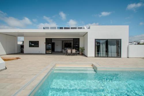 a villa with a swimming pool in front of a house at Casa Aulaga in Yaiza