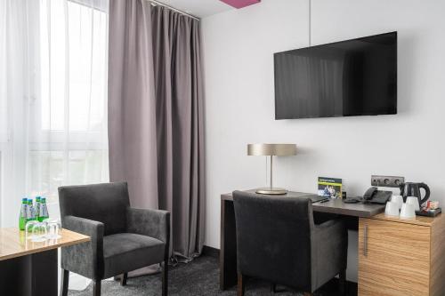 a room with a desk and two chairs and a television at B&B HOTEL Bytom in Bytom